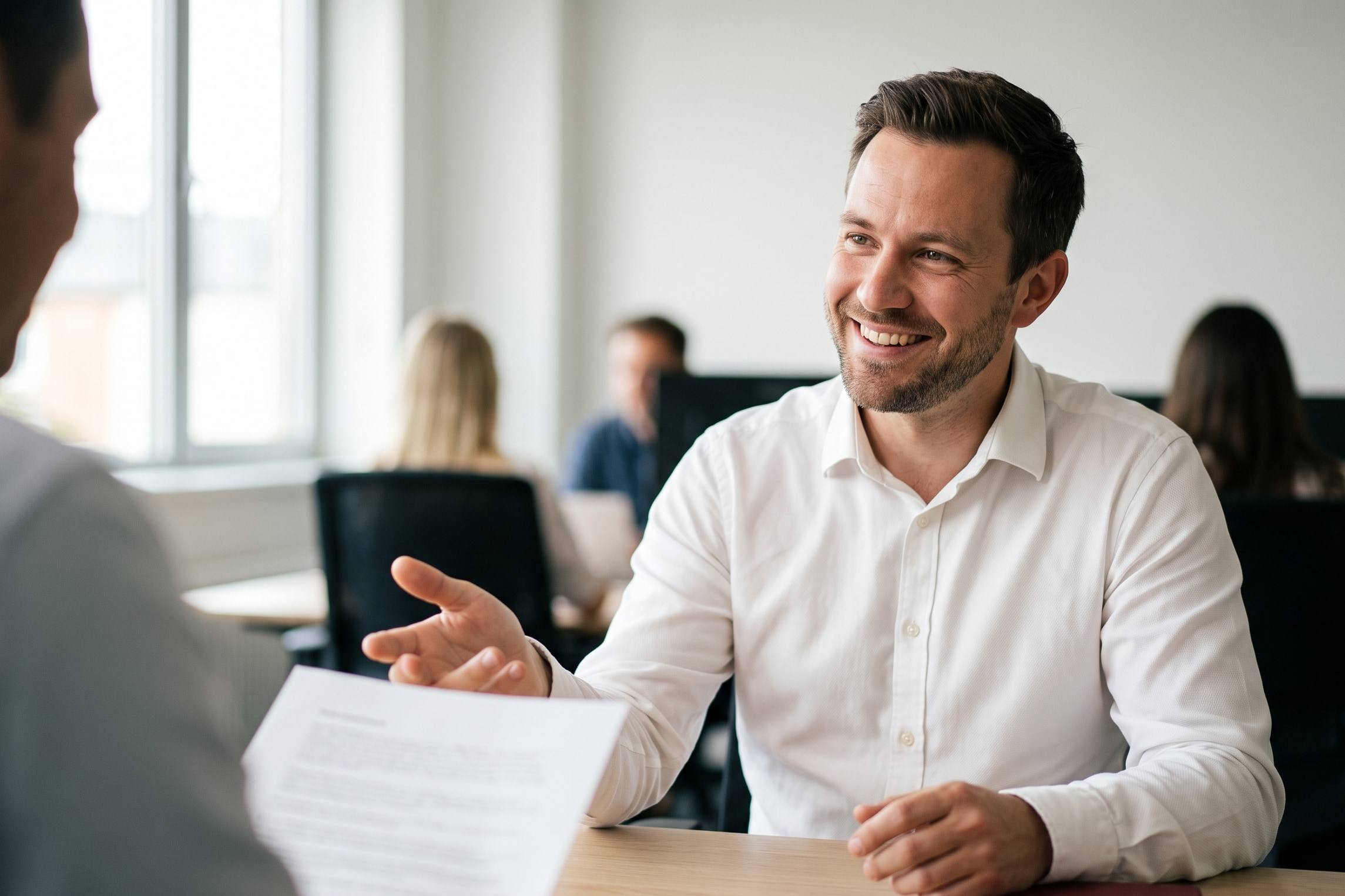 A specialist smiling as he talks a client through a document across a desk